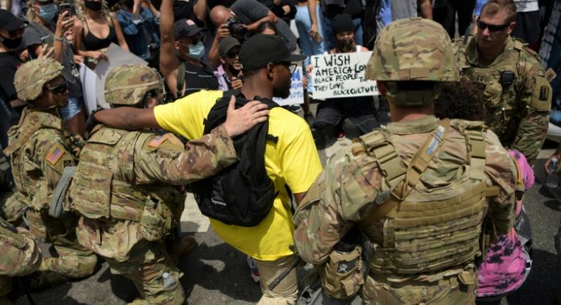 Protesters and members of the Army National Guard kneel together in Los Angeles on June 2, 2020 during a demonstration over the killing of George Floyd