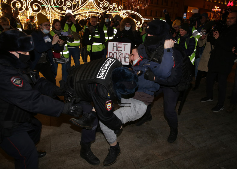 Funkcjonariusze policji zatrzymują mężczyznę trzymającego tabliczkę z napisem "Bez wojny" podczas protestu na placu Puszkinskaja 24 lutego 2022 r. w Moskwie