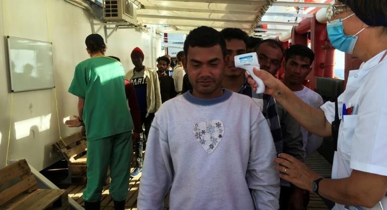 Anne (R) , a medic of French NGO SOS Mediterranee takes the temperature of migrants rescued by members of the boat Ocean Viking, off the coast of Italy's Lampedusa island