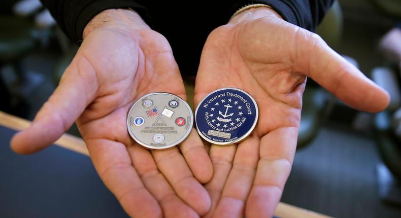 A retired Army National Guard officer holds coins, which are awarded to veterans who complete a treatment program, at the Kent County Courthouse in Warwick, Rhode Island on May 13, 2016.AP Photo/Charles Krupa