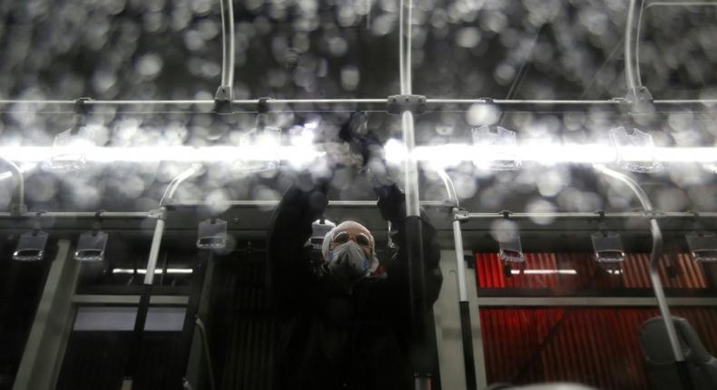 A city council worker in protective clothing disinfects a bus in Tehran as part of government efforts to control a novel coronavirus outbreak that has now killed 19 people