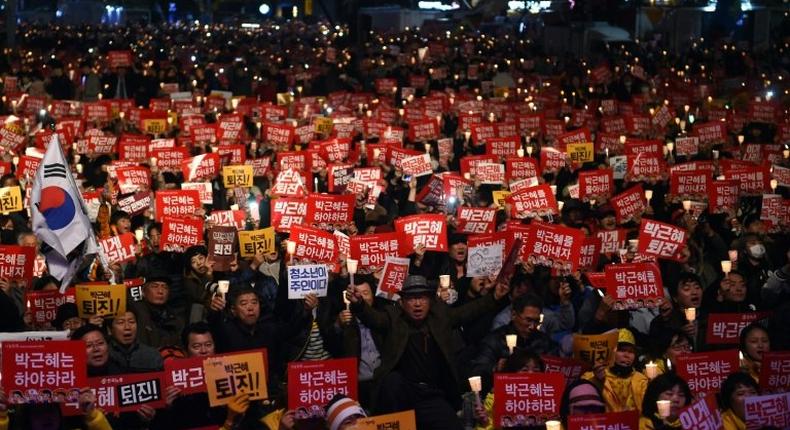 Protesters hold candles and banners calling for the resignation of South Korea's President Park Geun-Hye during an anti-government rally in central Seoul on November 19, 2016