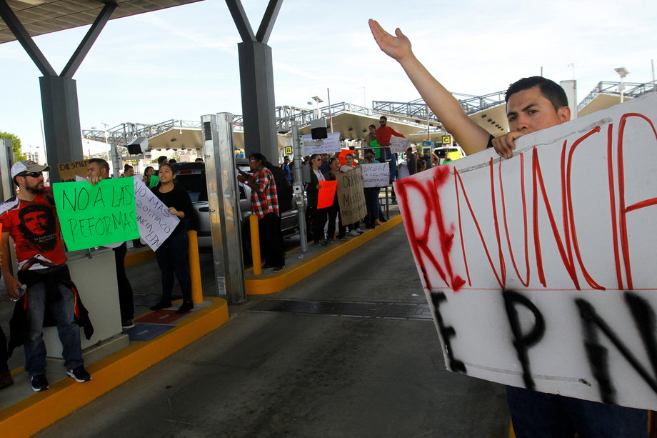 Demonstrators gesture as they allow duty-free access for vehicles during a protest against the rising prices of gasoline enforced by the Mexican government in El Chaparral, on the border crossing between the US and Mexico, in Tijuana, Mexico, January 8, 2017. The signs reads, "No to reforms" and "EPN resignation."