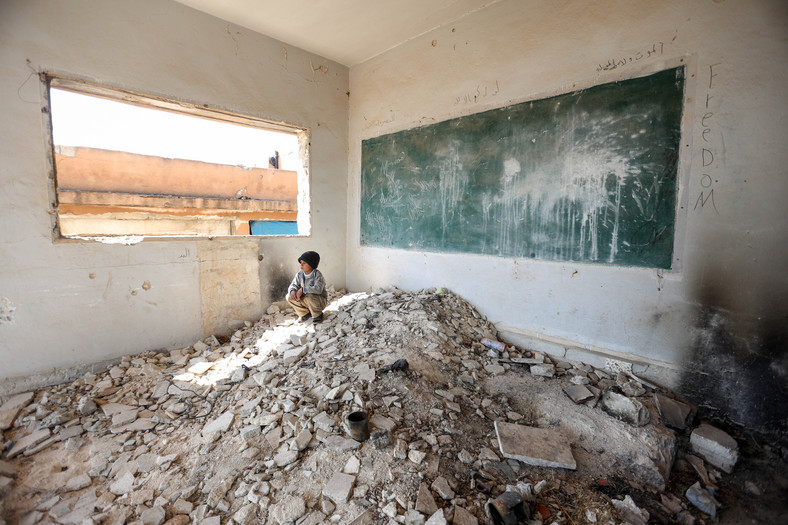 Syryjski chłopiec pośród ruin szkoły po bombardowania z rozkazu Assada i wspierającej go Rosji