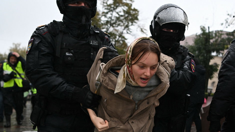 Milicjanci prowadzący obezwładnioną kobietę podczas protestów przeciw powszechnej mobilizacji w Moskwie