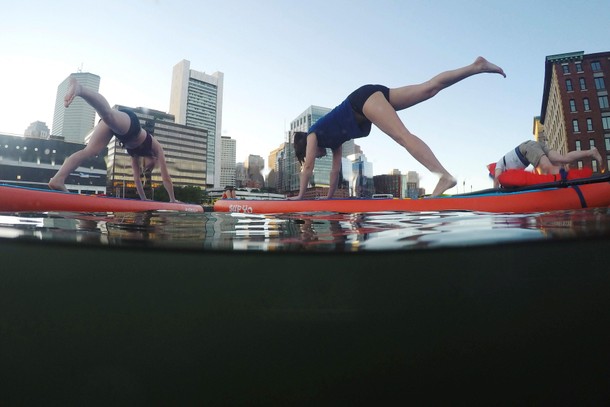 People take part in a Sup Yo, Boston stand up paddle board yoga class on Fort Point Channel on Int