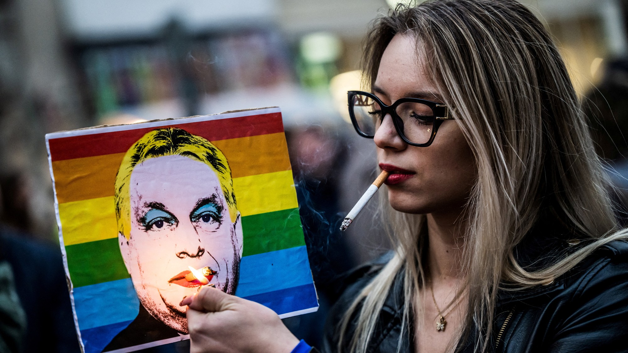 Žena si počas demonštrácie zapaľuje cigaretu umiestnenú na plagáte s vyobrazením maďarského premiéra Viktora Orbána po tom, ako maďarský parlament schválil zákon, ktorý zakazuje komunitám LGBTQ+ organizovať každoročný pochod Pride.