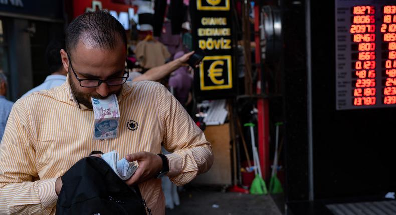 A customer holds Turkish lira banknotes outside a currency changer on a street in Istanbul on September 6, 2022.