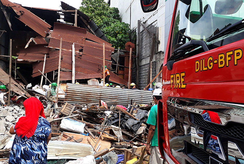 Workers clear concrete debris as they search for possible casualties at the ruins of an old building