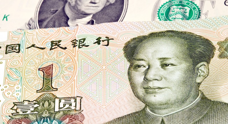 One Chinese yuan bill lying on top of a US dollar bill.Getty Images