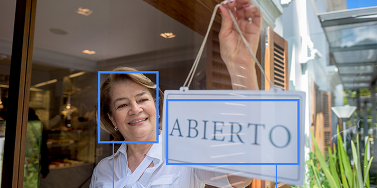 Google Cloud Vision, being used to identify that a person is smiling and that the text on the sign is in Spanish.