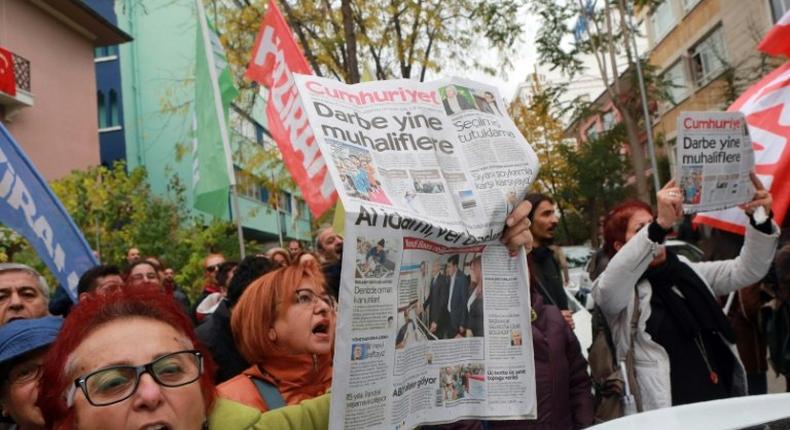 People hold the latest copy of Turkish newspaper Cumhuriyet outside its headquarters in Ankara, chanting that a free media could not be silenced