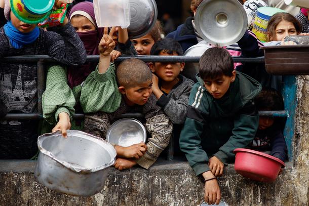 Palestyńskie dzieci czekają na wydanie posiłku w jednym z punktów pomocowych w Rafah