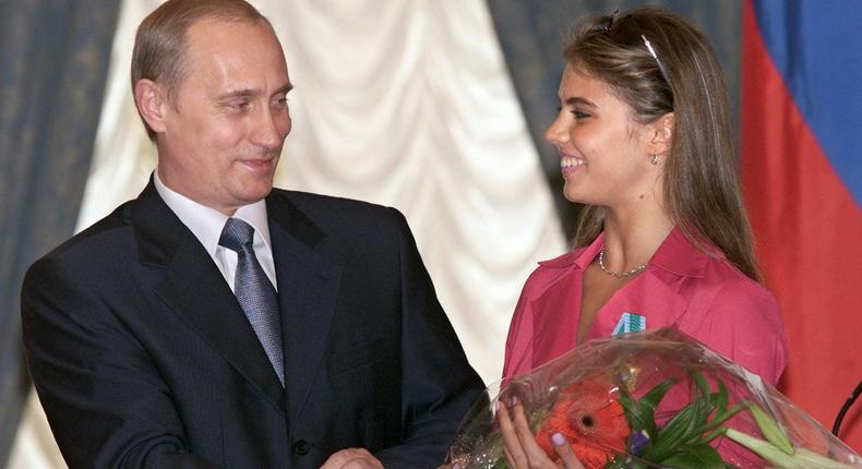 Russian President Vladimir Putin (L) hands flowers to Alina Kabayeva, Russian rhytmic gymnastics star and Olympic prize winner, after awarding her with an Order of Friendship during annual award ceremony in the Kremlin 08 June 2001.