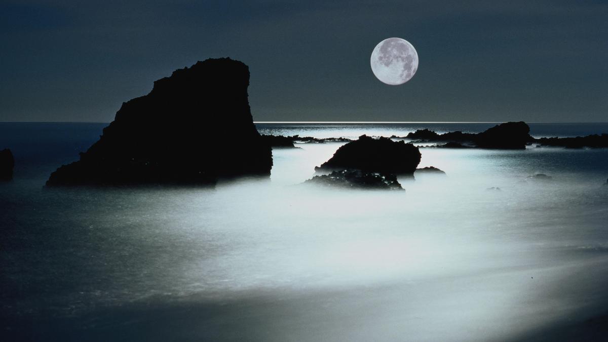 Full moon over rocky shoreline