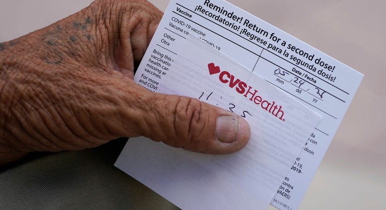 A man holds his vaccination reminder card after having received his first shot.
