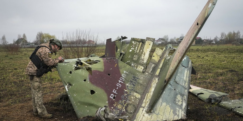 Ukraiński żołnierz ogląda fragment odrzutowca Su-25 rosyjskich sił powietrznych po bitwie we wsi Kolonszczyna w Ukrainie, 21 kwietnia 2022 r.