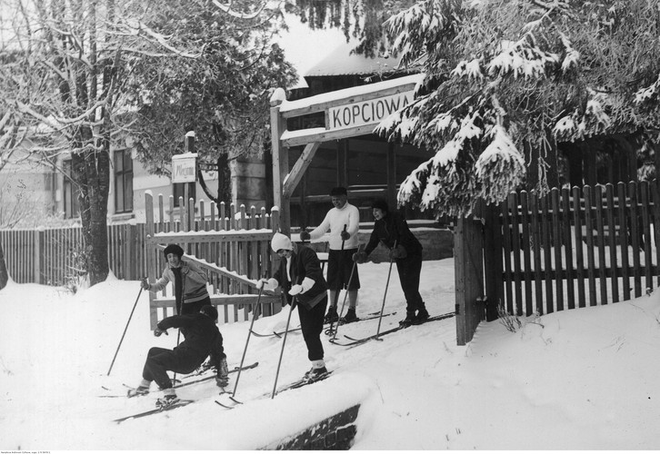 Grupa turystów na nartach przed drewnianą bramą
