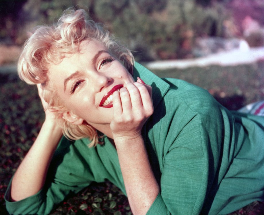 Actress Marilyn Monroe poses for a portrait laying on the grass in 1954 in Palm Springs, California.