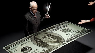 Businessman holding scissors and reaching hands around one hundred dollar bill