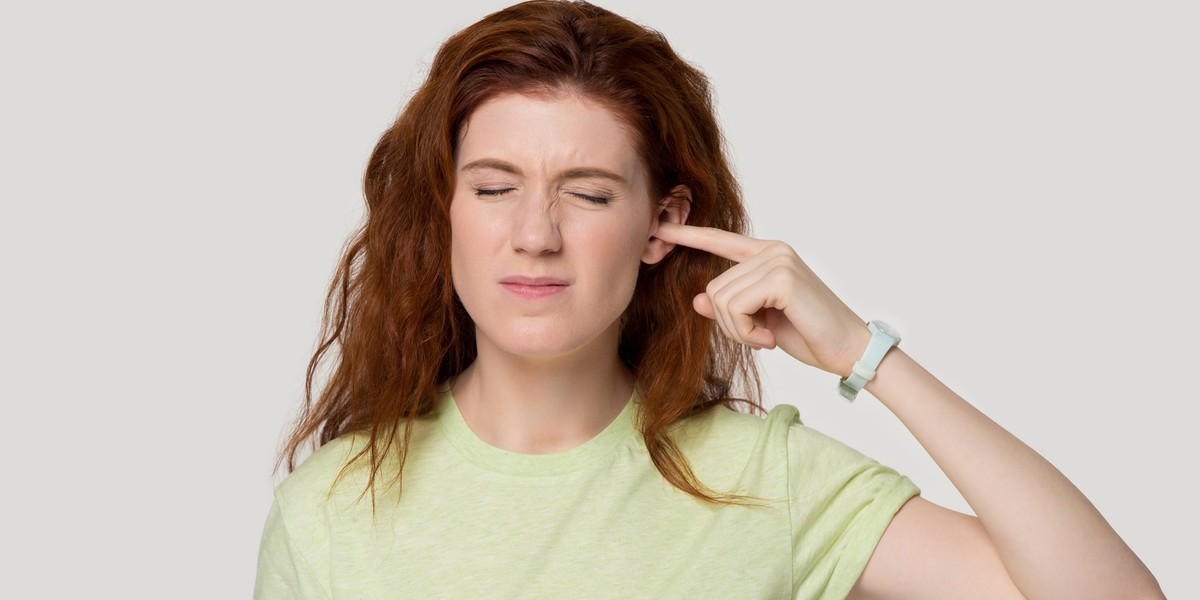 Studio headshot young woman suffering from ear pain or noise