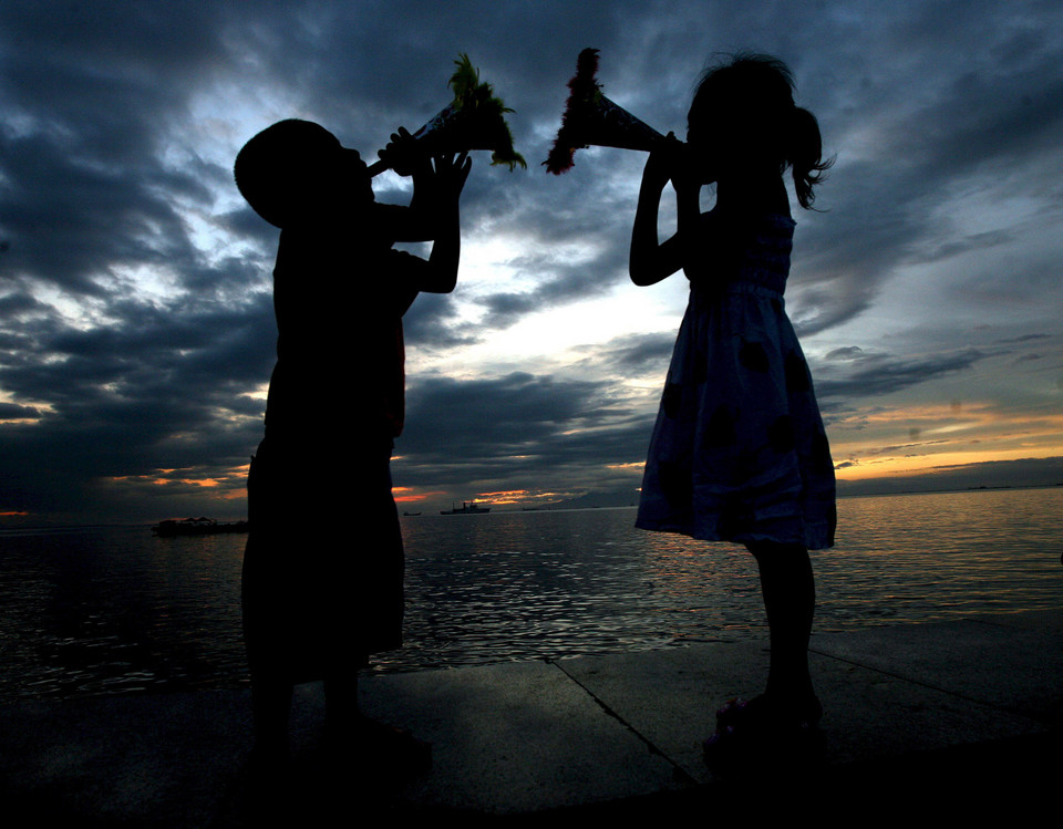 Filipińskie dzieci grają na trąbkach na promenadzie w Manili