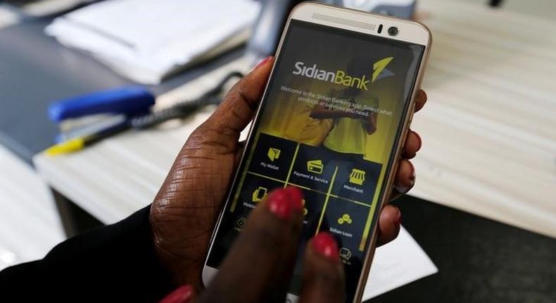 A customer uses her cell-phone to access the Sidian Bank mobile-app inside the banking hall at the Sidian Bank headquarters on the outskirts of Kenya's capital Nairobi, June 29, 2016. Picture taken June 29, 2016. 