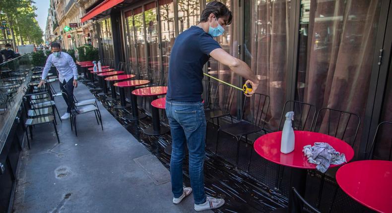 Pierre-Antoine Boureau handling a tape measure as he prepares the terrace of a restaurant in order to respect distancing to help curb the spread of the coronavirus in Paris, Monday, June 1, 2020. France is reopening its restaurants, bars and cafes starting tomorrow as the country eases most restrictions amid the coronavirus crisis. (AP Photo/Michel Euler)