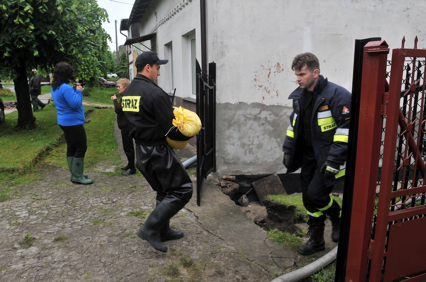 strażacy noszą worki z piaskiem