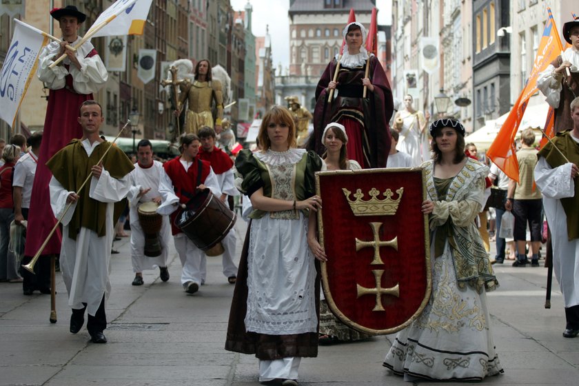 Osoby przebrane w historyczne stroje idą przez centrum Gdańska