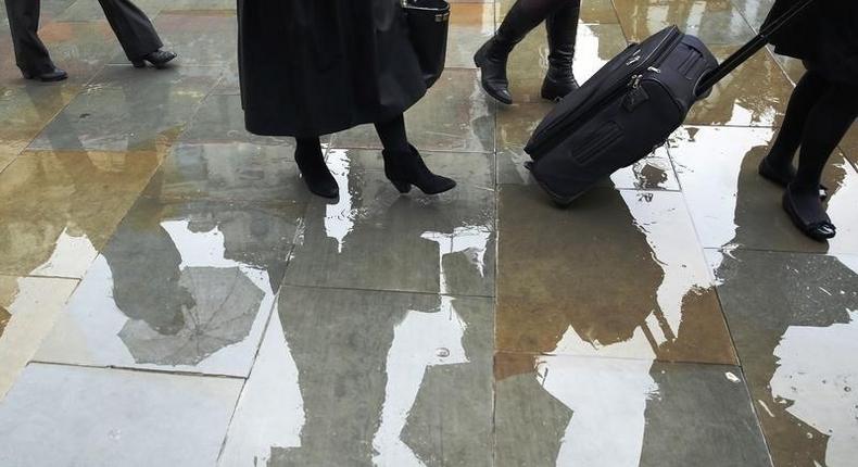 People queue to enter the court building during a heavy rain storm outside the High Court in London November 14, 2014. REUTERS/Luke MacGregor