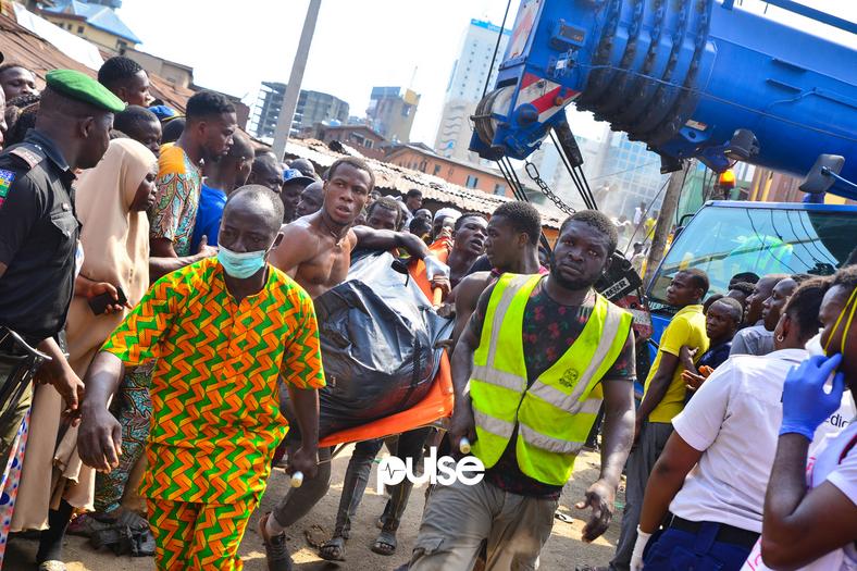 A corpse being taken away from the site of the collapsed building (Pulse) 