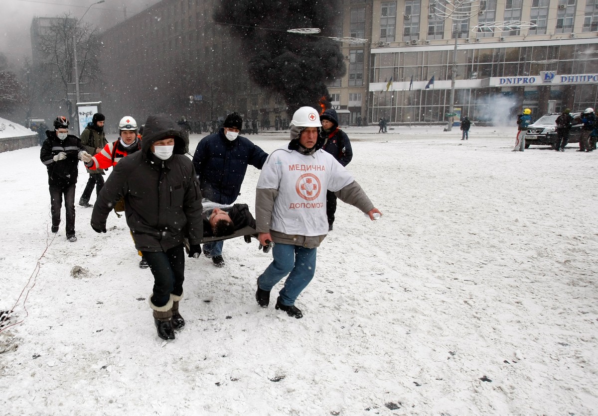 Demonstranci niosą rannego w czasie starć na Majdanie