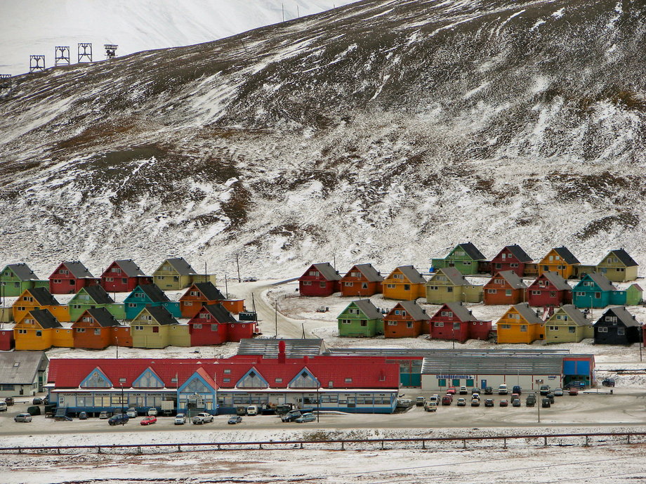 Miasto Longyearbyen (Svalbard, Norwegia). Kolorowe domy kontrastują tu z posępną scenerią. Duży budynek na pierwszym planie stanowi centrum usługowe miasta i archipelagu. Znajdują się tam m.in. sklepy, placówki bankowe i pocztowe.