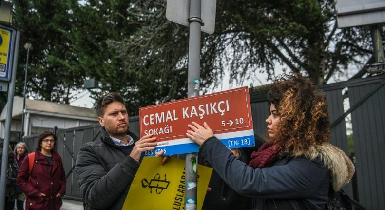 Members of Amnesty International hang a sign reading Jamal Khashoggi Street where the Saudi Arabian consulate is located in Istanbul, during a ceremony marking 100 days since the murder of the journalist there