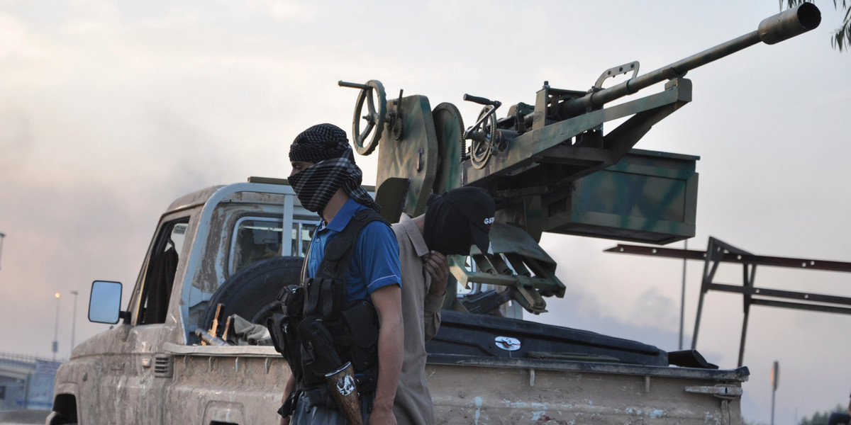 ISIS fighters stand guard at a checkpoint in Mosul, Iraq, on June 11, 2014.