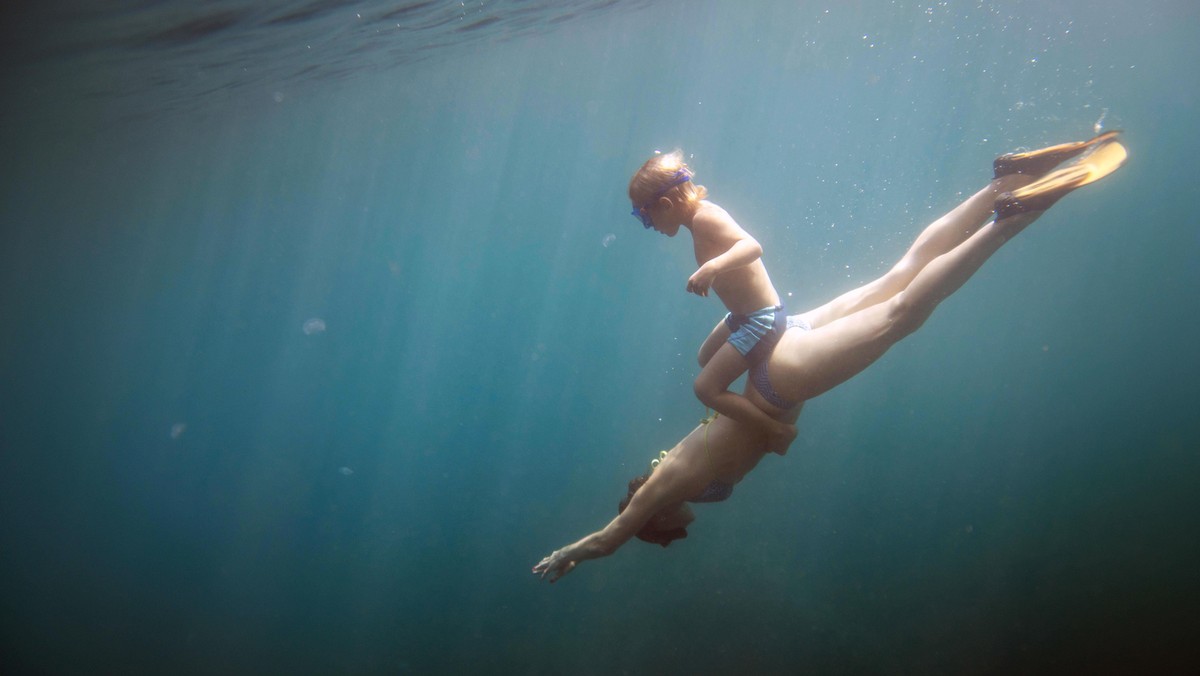 Underwater view of boy and mother diving