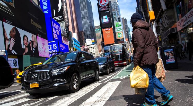 Férfi műanyag zacskóval a kezében sétál a Times Square-en