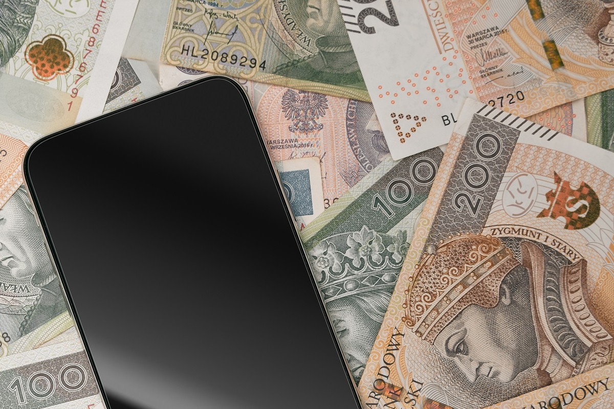 Smartfon na tle polskich banknotów - jako ilustracja opłaty reprograficznej od 2026 roku