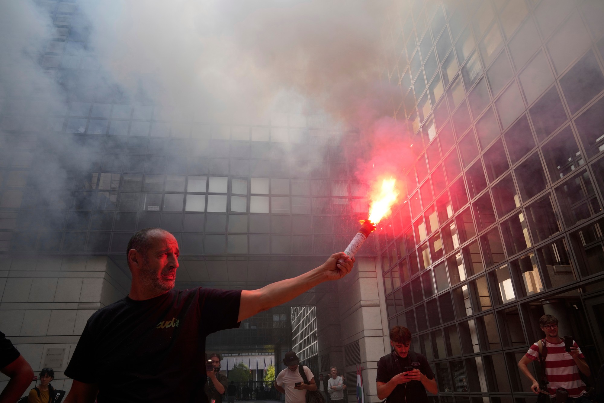 Demonštrant zapaľuje svetlicu pred ministerstvom hospodárstva počas protestu.