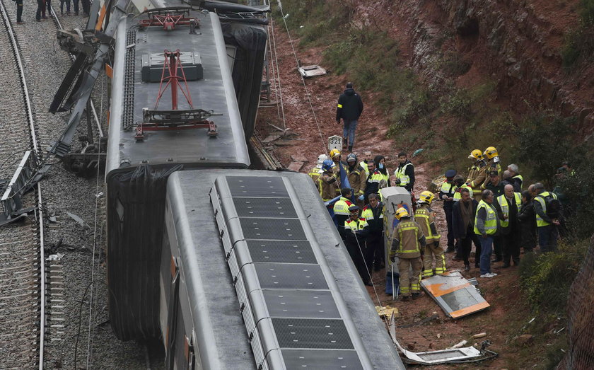 Firefighters, police and other officials survey the scene after a commuter train derailed between Te