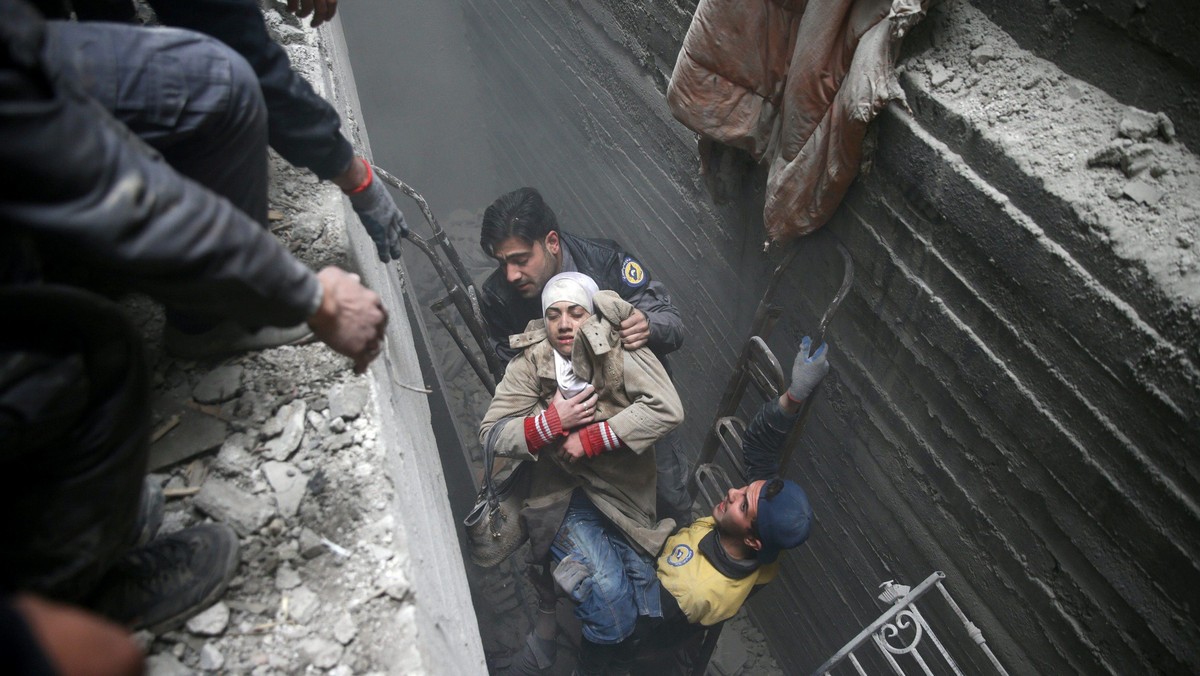 Syria Civil Defence members help an unconscious woman from a shelter in the besieged town of Douma