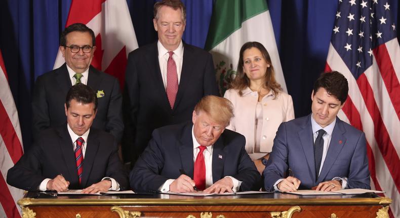 FILE - In this Nov. 30, 2018 file photo, President Donald Trump, center, sits between Canada's Prime Minister Justin Trudeau, right, and Mexico's President Enrique Pena Nieto as they sign a new United States-Mexico-Canada Agreement that is replacing the NAFTA trade deal, during a ceremony at a hotel before the start of the G20 summit in Buenos Aires, Argentina. Trumps new North America trade agreement would give the U.S. economy only a modest boost, an independent federal agency finds. (AP Photo/Martin Mejia, File)