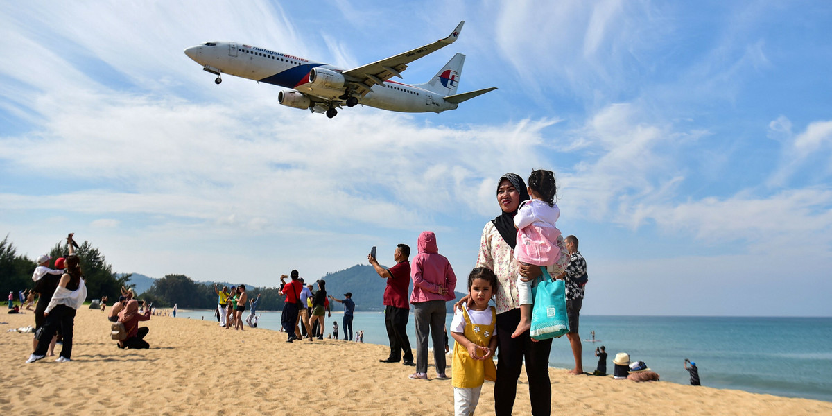 Tajlandia. Turyści pozują do zdjęcia na plaży Mai Khao, gdy samolot ląduje na międzynarodowym lotnisku Phuket, 13 lutego 2023 r.