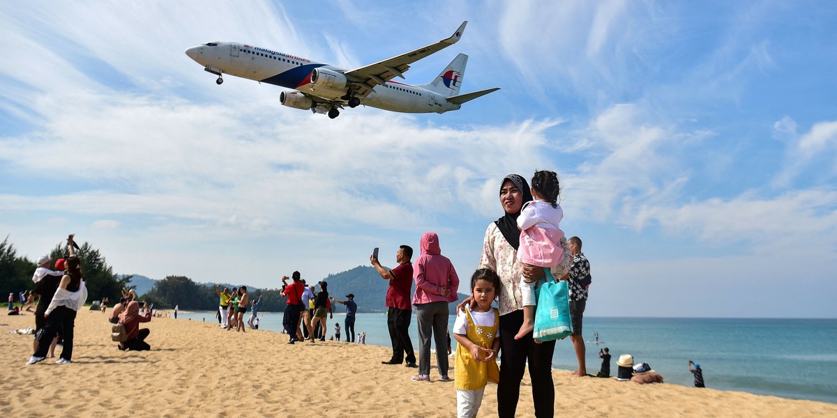 Tajlandia. Turyści pozują do zdjęcia na plaży Mai Khao, gdy samolot ląduje na międzynarodowym lotnisku Phuket, 13 lutego 2023 r.