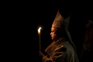 The Archbishop of Malta, Charles Scicluna, carries a candle at the start of an Easter vigil mass at St John's Co-Cathedral in Valletta