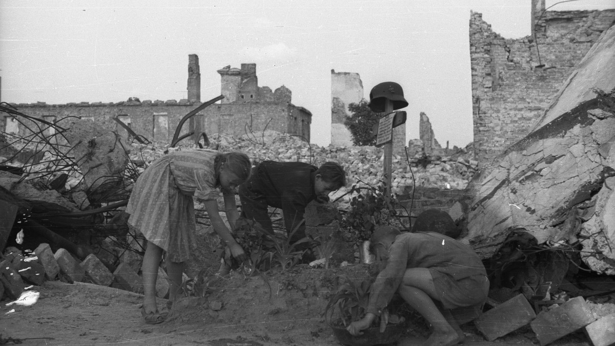 Dzieci porządkują mogiłę powstańca warszawskiego wśród ruin (1947 r.)