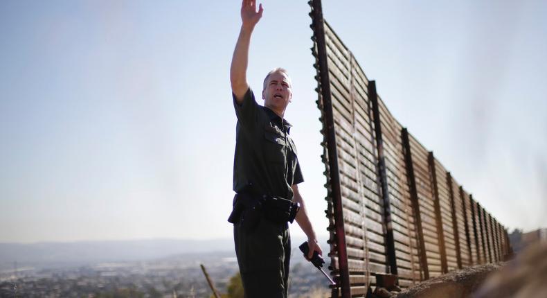 US Border Patrol agent Jerry Conlin looks out over Tijuana, Mexico, behind, along the old border wall along the US - Mexico border