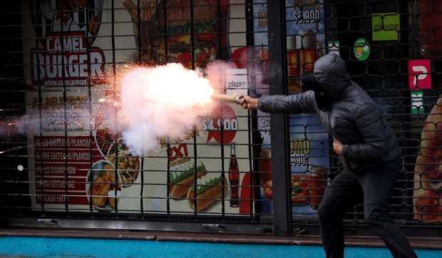 Demonstrant ispaljuje baklju tokom sukoba na protestu u Santjagu | Foto: Reuters