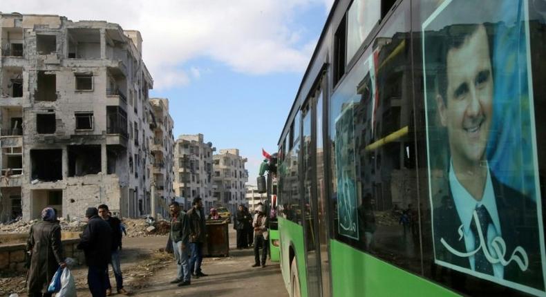 Syrians, from various western districts, wait at a bus stop in Aleppo's central Jamiliyeh neighbourhood before taking part in a bus trip through government-held territory of the divided city